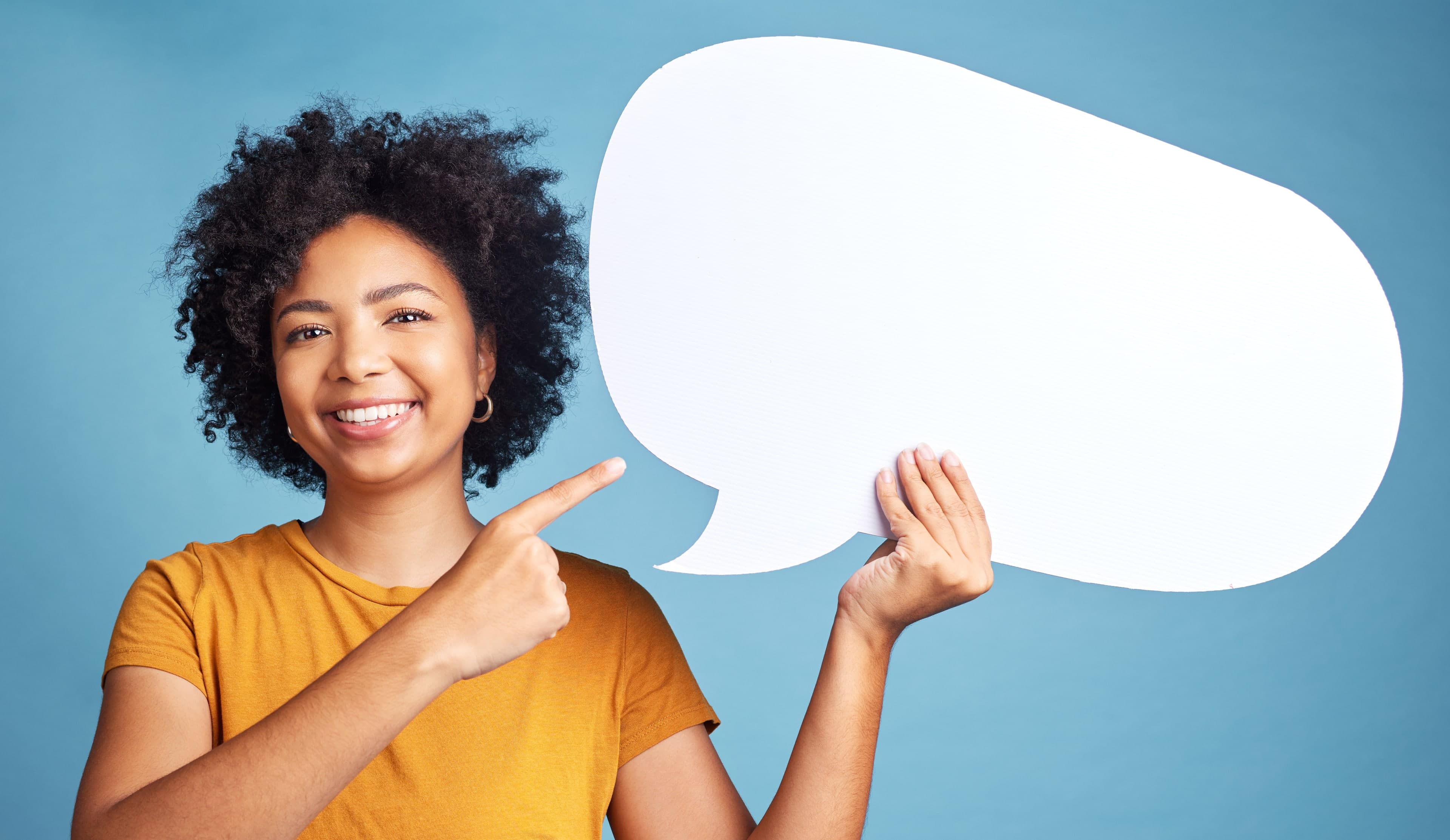 Woman in a mustard top points toward a blank white speech bubble against a blue background.